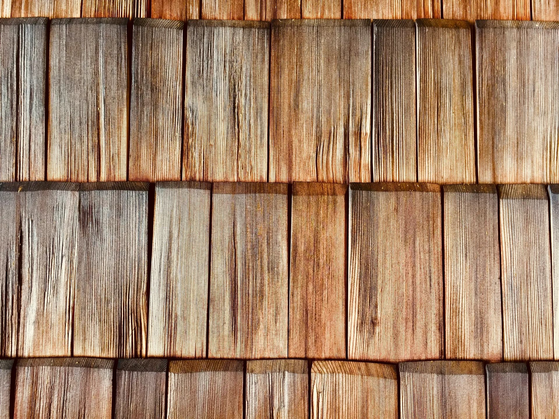 Weathered cedar wood shingles in overlapping rows showing natural grain patterns and brown tones