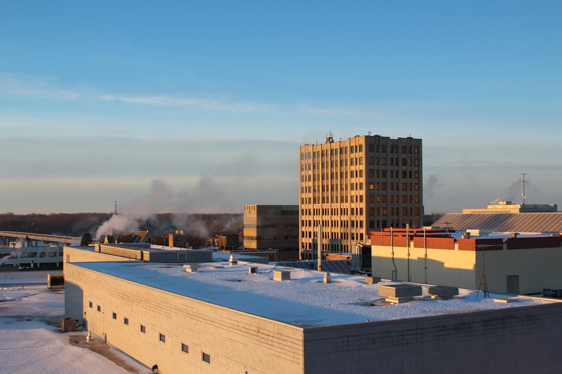 Winter cityscape with snow-covered buildings and tall office tower during golden hour lighting