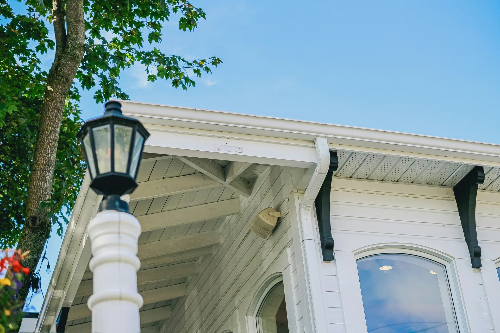 Victorian house with decorative white trim and vintage street lamp against blue sky