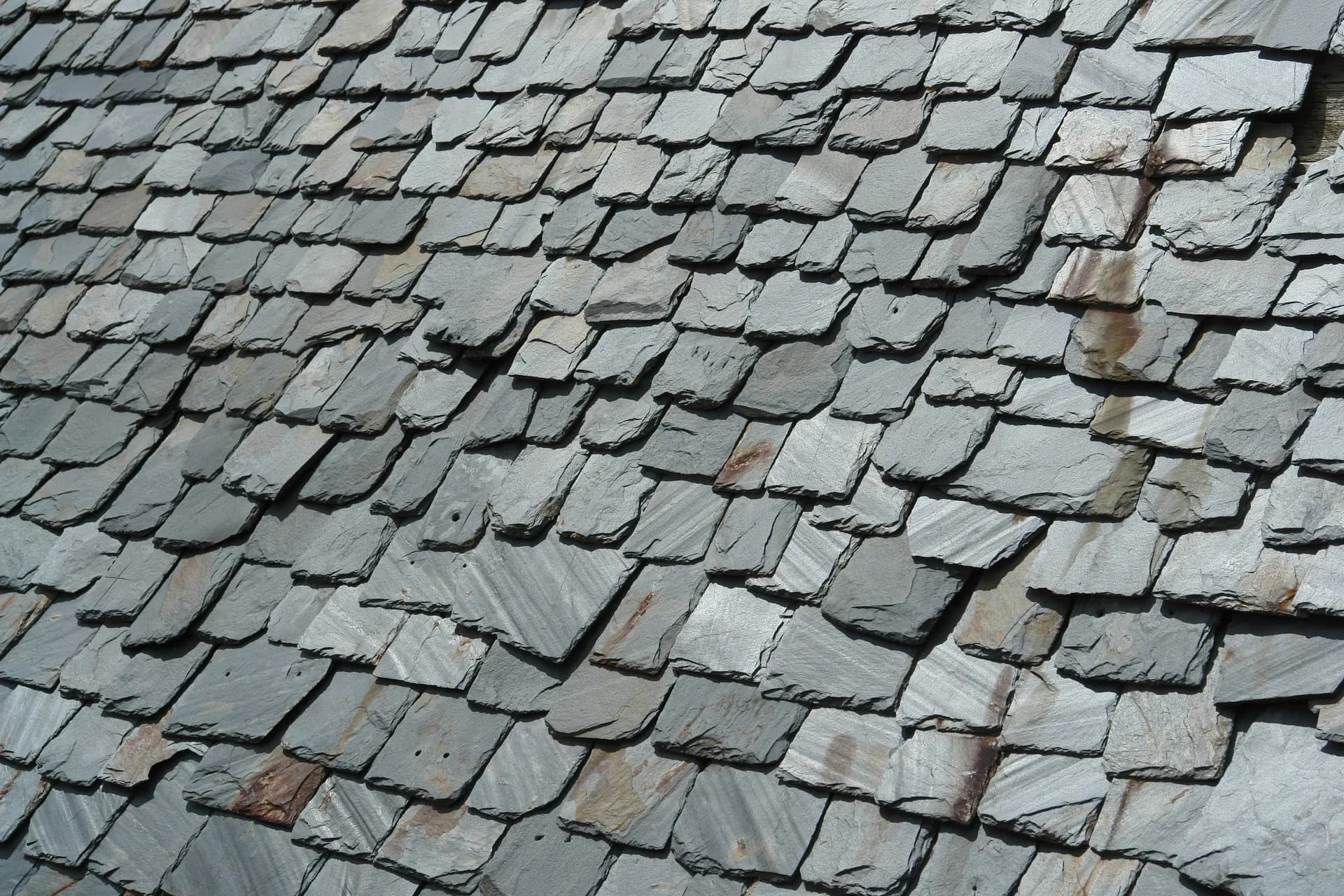Weathered gray slate roof tiles arranged in overlapping rows showing natural stone texture and aging