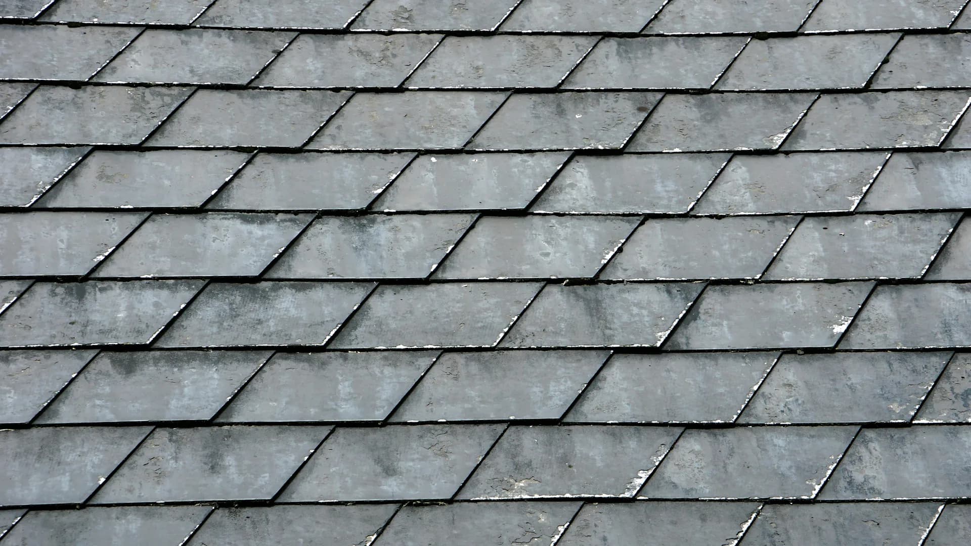 Weathered gray slate roof tiles arranged in overlapping diamond pattern rows